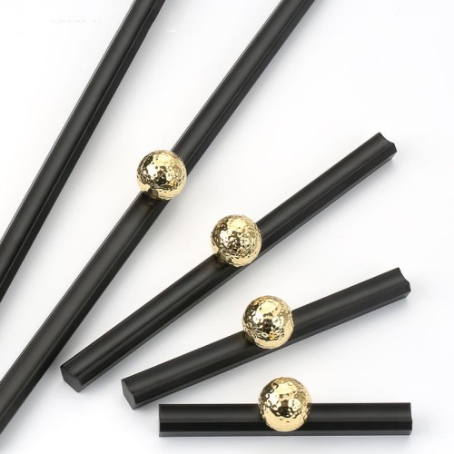 Möbelgriff Nigua – schwarzer länglicher Griff mit dekorativer goldener Kugel für Schränke und Schubladen, moderner Aufsatzgriff, erhältlich im Shop egriffe.de.
