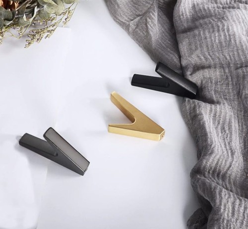 Wandhaken Bola – minimalistischer geometrischer Haken für Zuhause, Büro und Hotels. Aus robustem Metall, einfache Montage mit Schrauben im Set. Farben: Schwarz, Perlgrau und gebürstetes Gold.
